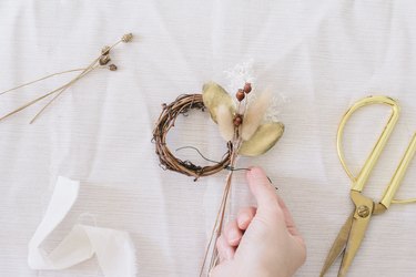 Tying floral bundle to mini grapevine wreath