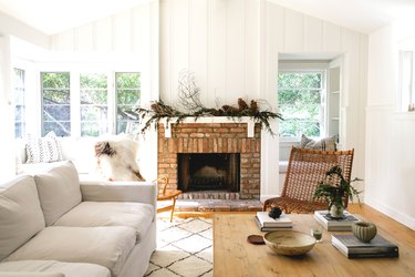 brick fireplace with white mantle decorated with pine cone garland arrangement