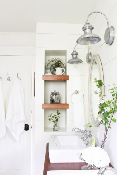 Rustic accents on wooden shelves in a white bathroom