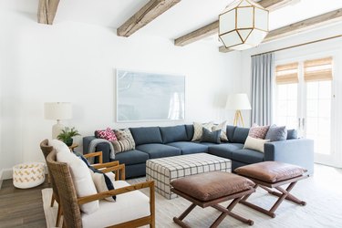 farmhouse family room idea with blue sectional and wood ceiling beams