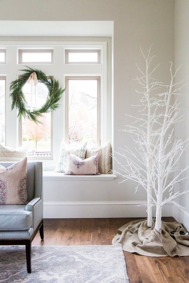 White Christmas Tree Ideas with White painted tree branches, window seat, evergreen wreath hung in window.