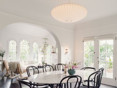 white living and dining room with table, and arched windows