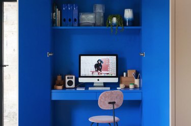 cobalt blue home office tucked in a closet with desk and shelving