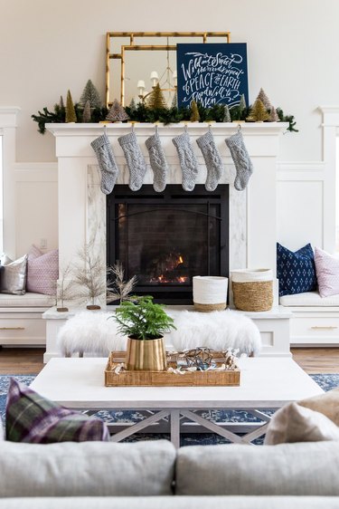 Whit living room with a fireplace with silver stockings and gold mirrors