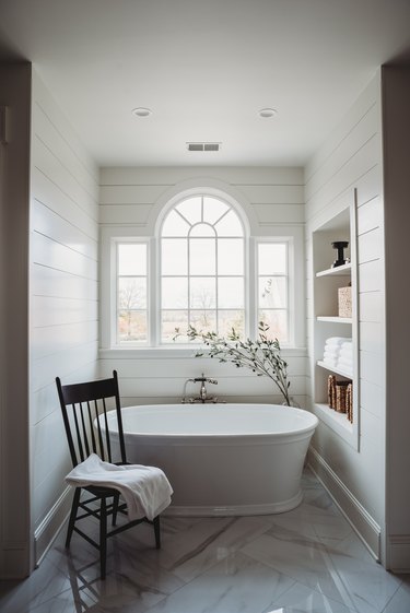 white bathroom with tub and arched window