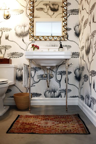 bathroom idea with console sink and patterned wallpaper with decorative mirror