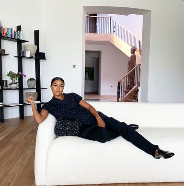 Gabrielle Union-Wade on white couch with black shelves in background