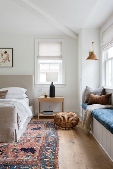 white bedroom color idea with colorful rug and blue window seat