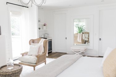 white farmhouse bedroom with wingback lounge chair seating area