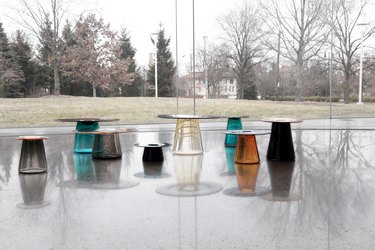 a set of glass tables near windows with tress in the background