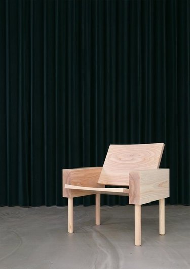 wooden chair on concrete floor with dark curtain in the background
