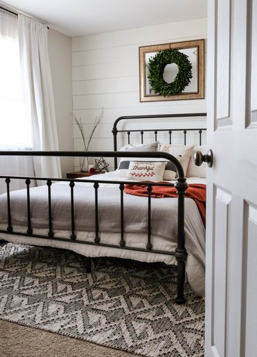 farmhouse bedroom with shiplap accent wall and iron bed frame