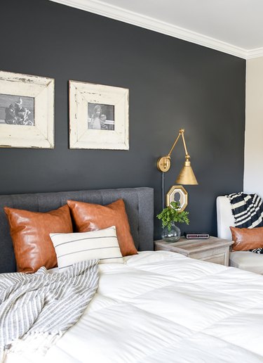farmhouse bedroom with dark gray accent wall and brass wall sconces