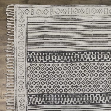 Gray are rug with short fringe and subtle stripes with geometric designs