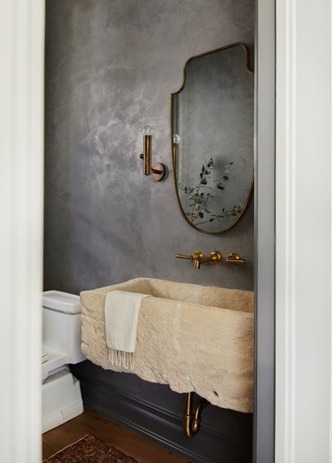 bathroom with charcoal gray lime wash walls and brass accent