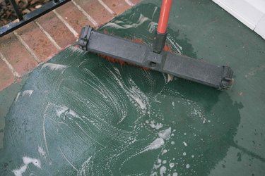 Cleaning concrete porch with degreaser and broom