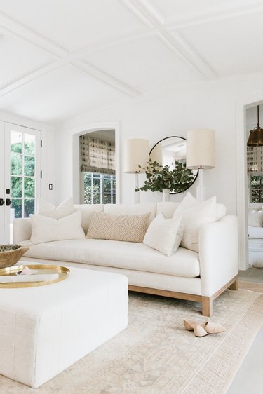 white living room with plush sofa and ottoman