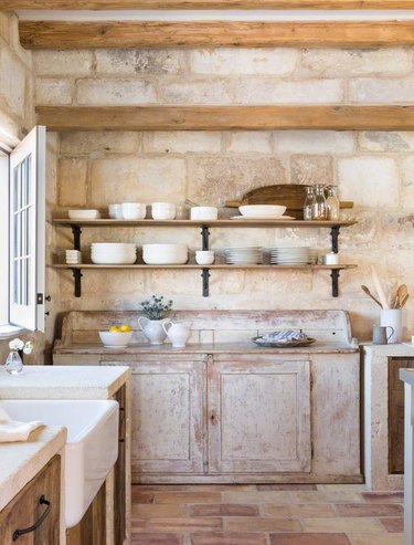 country kitchen with brick flooring and walls and weathered cabinetry