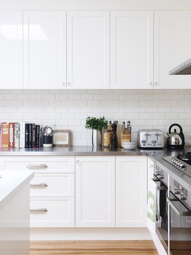 white kitchen with stainless steel countertops and white subway tile backsplash