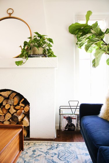 white living room with green plants and stacked wood