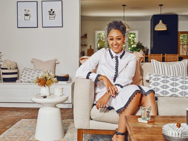 Tia Mowry sitting on couch near white side table