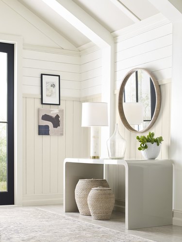 entryway space with a round mirror and white walls