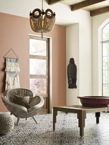 room with table, chair, and wall hanging with peach-colored wall