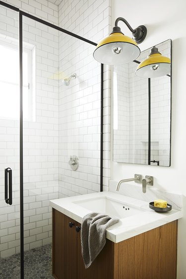 small minimalist bathroom with yellow sconce above the vanity