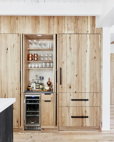 wood kitchen cabinet design with black hardware and matching wood flooring