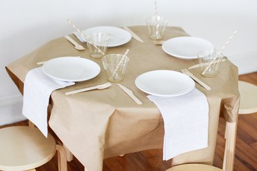 Kraft paper on table with plates, cups and utensils