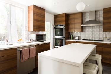 Midcentury kitchen with wood cabinets and white tile backsplash, white kitchen island