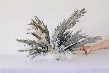 Placing dried centaurea pods into vase