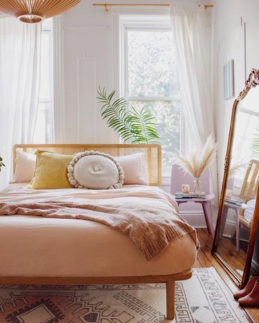 Sunset-inspired bedroom with drapery at windows and framed mirror leaning against the wall