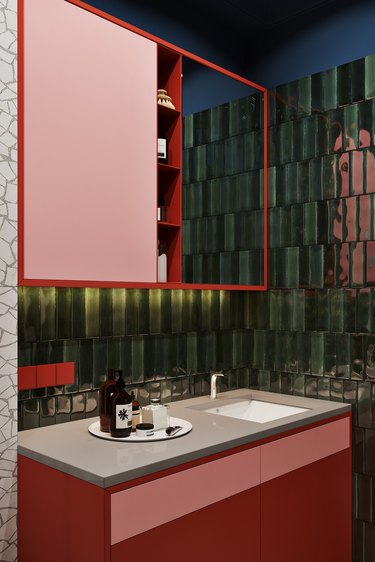 bathroom with red vanity cabinet and green textured tile walls