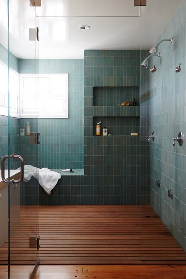 teal shower tile in walk-in with wooden floors