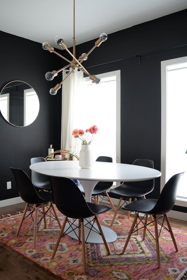 black dining room color idea with brass lighting and black chairs