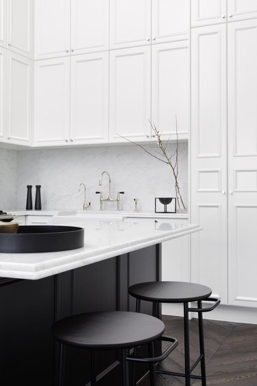 black and white kitchen with white cabinetry and black island and furniture