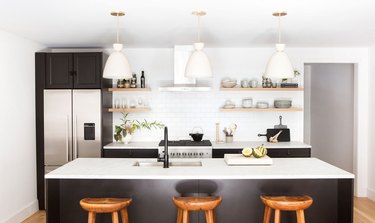 black and white kitchen with open shelving and white pendant lighting