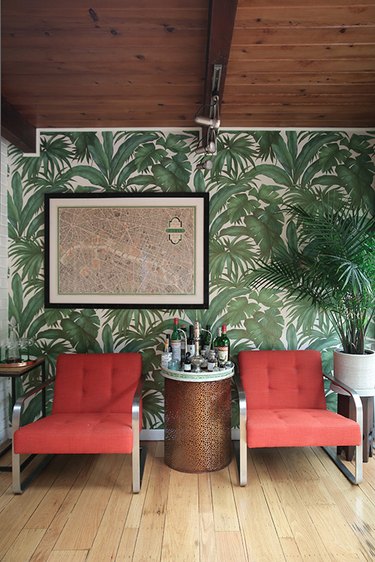 tropical wallpaper with red lounge chairs and wood beam ceiling