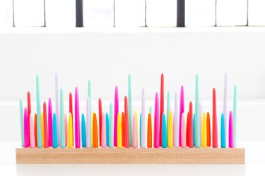 Colorful neon candles in a wooden holder