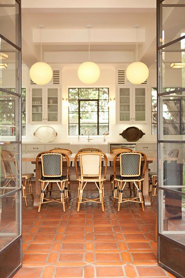 white kitchen with bistro dining chairs and terra cotta kitchen flooring