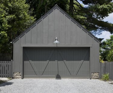 Detached Garage Ideas with stone and black wood detached garage with black dual garage doors.