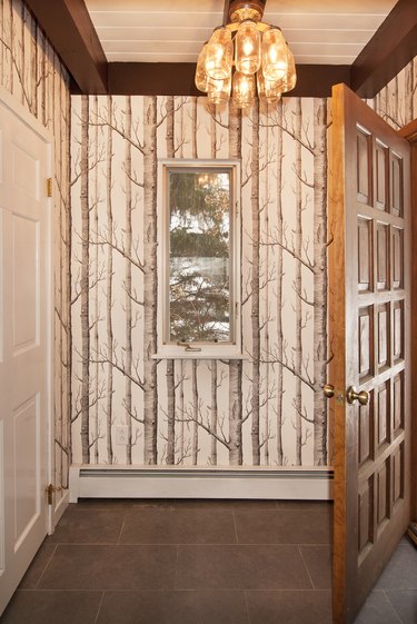 Hallway with pendant light and wallpaper with a trees design