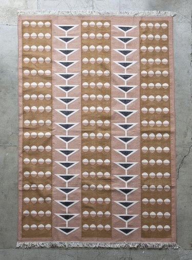 Beige and blush area rug with black accents and geometric striped design