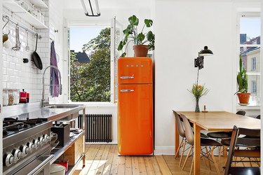 fresh and airy kitchen color idea with bright orange fridge