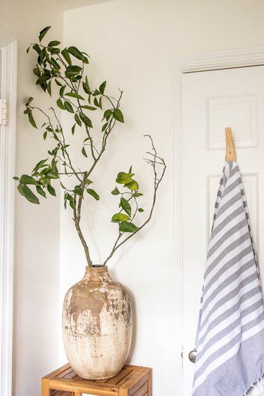 oversized ceramic jug vase filled with large branches in bathroom next to Turkish towel