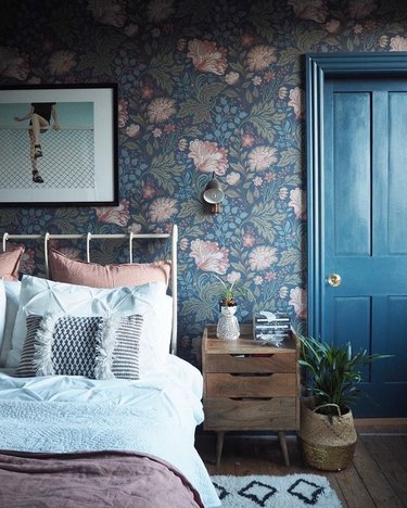 country bedroom idea with blue door and floral wallpaper