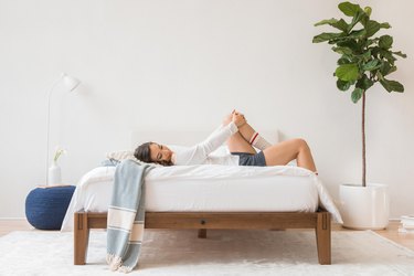 person on bed with plant nearby