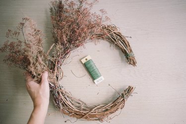 Tying dried floral bundles onto grapevine wreath with floral wire