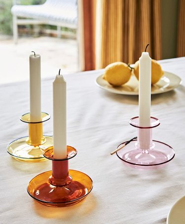 white candlestick in colorful candle holders on white tablecloth